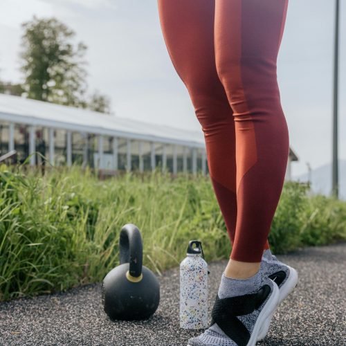 A person exercising outdoors with a kettlebell and water bottle, promoting fitness.
